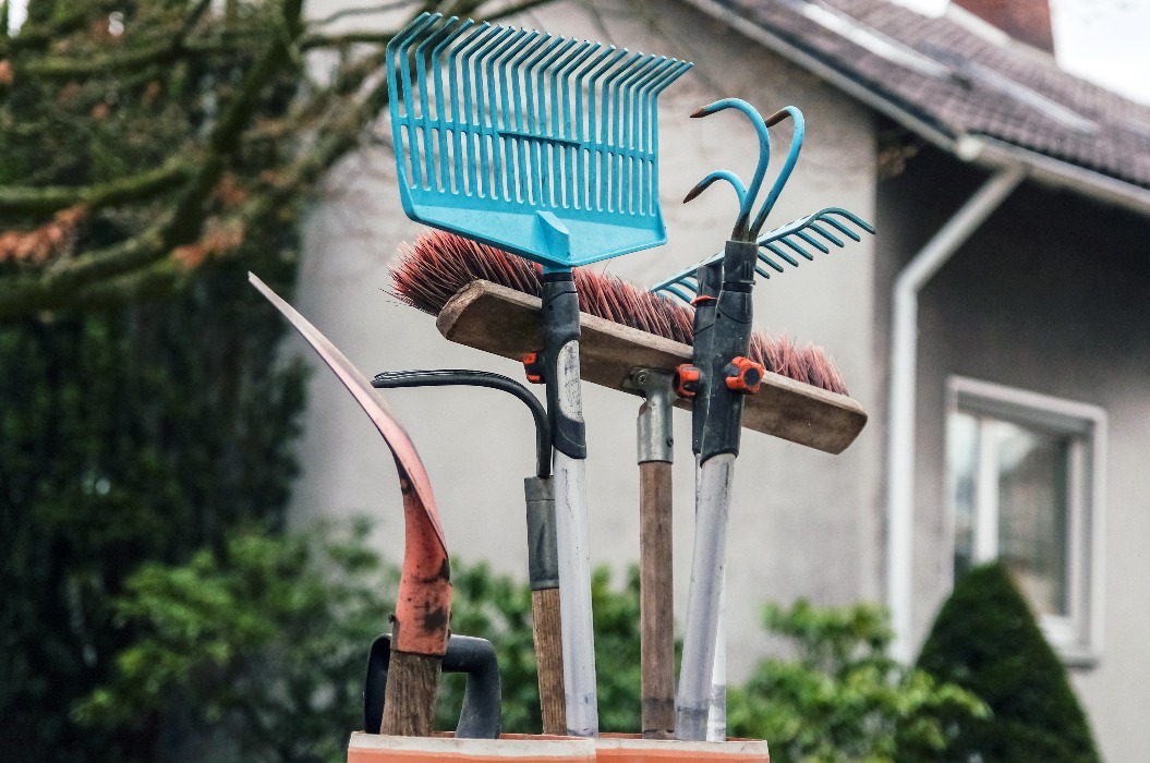 Konzept Hausmeisterservice: Besen, Rechen, Schaufeln und andere Werkzeuge für Haus und Garten in Nahaufnahme vor einem Haus, Copy Space